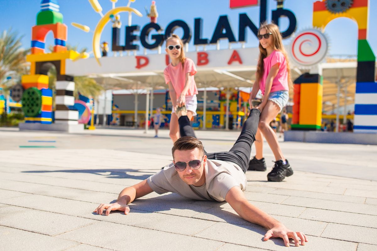 2 Kids Dragging Their Father At Legoland Dubai For The Best Places To Visit In Dubai This Summer