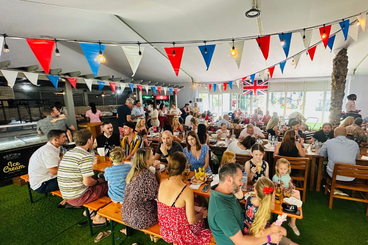 People gathered under a festive banner for brunch with their families at Beside the Seaside Brunch at Reform The Lakes Dubai, best things to do in Dubai this Eid Al Adha