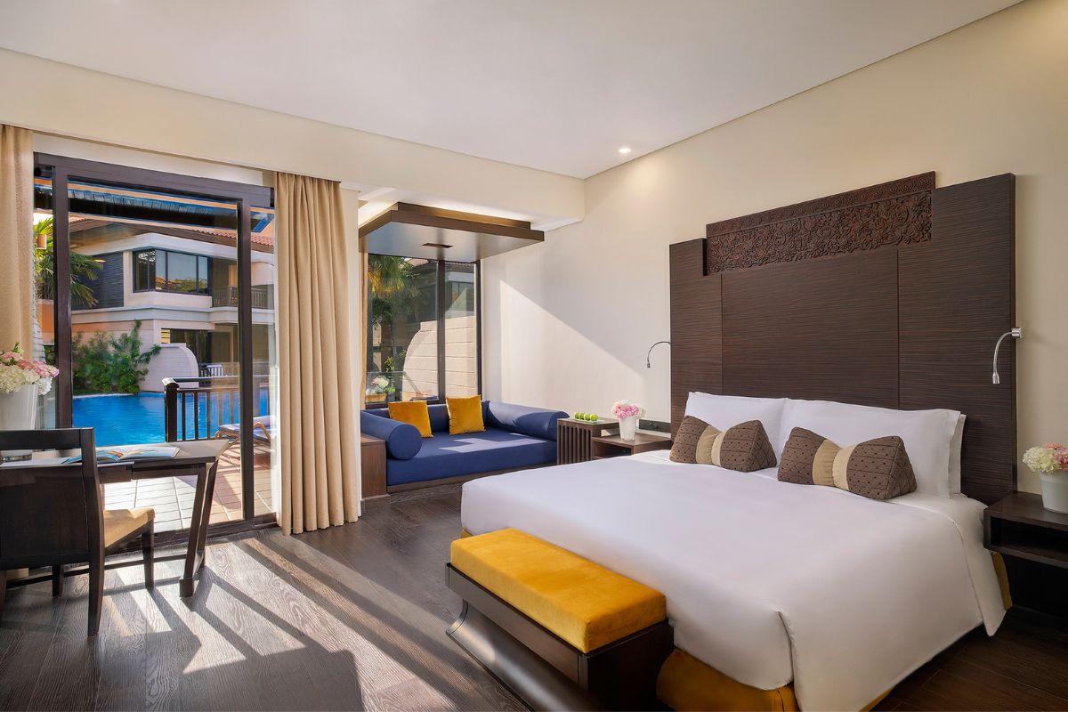 Deluxe Room With A King Size Bed. Sofa On The Left Side And Glass Overlooking View And Pool Outside At Anantara The Palm Dubai Resort Staycation