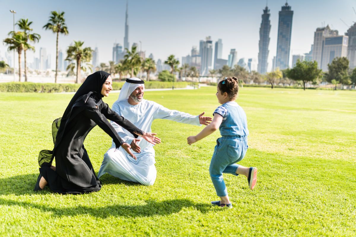 A Kid Running Towards Her Emirati Parents Enjoying A Day Outside In Dubai For Eid Al Adha