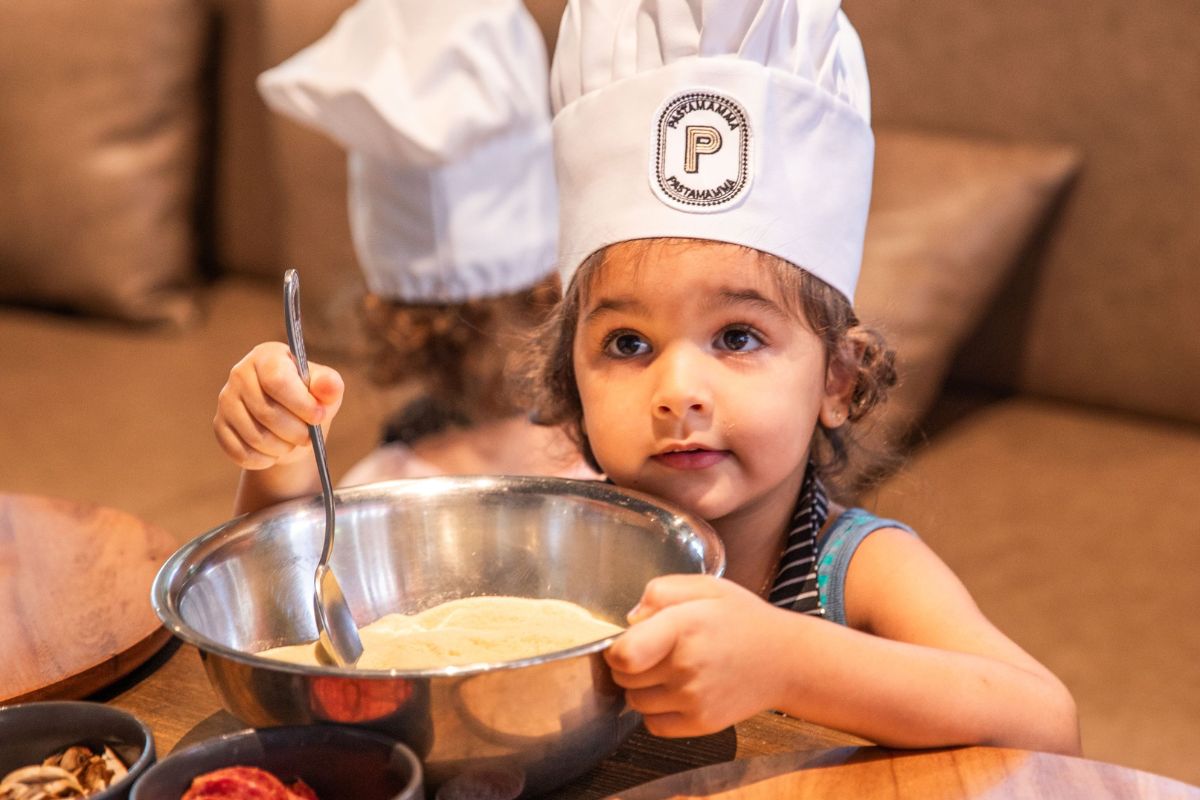 A Little Girl With A Toque Making Pasta For The Best Indoor Things To Do For Kids This Summer