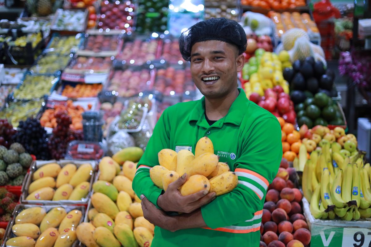 Waterfront Market Mangolicious In Dubai Featuring A Man Holding Loads Of Delicious Mangoes