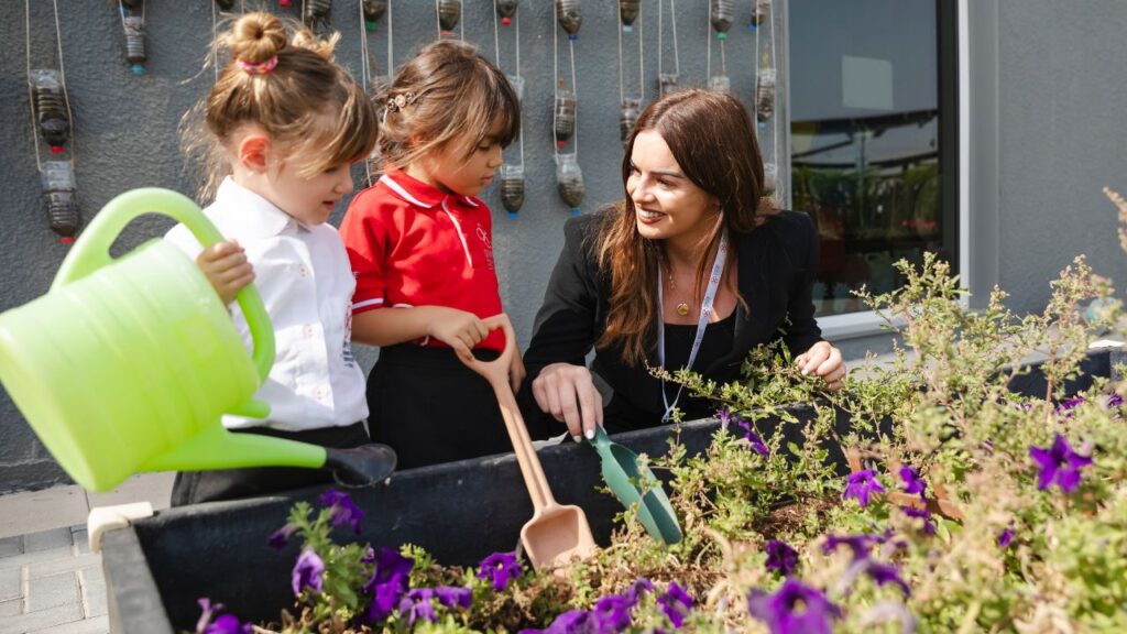 teacher with her young students watering the garden
