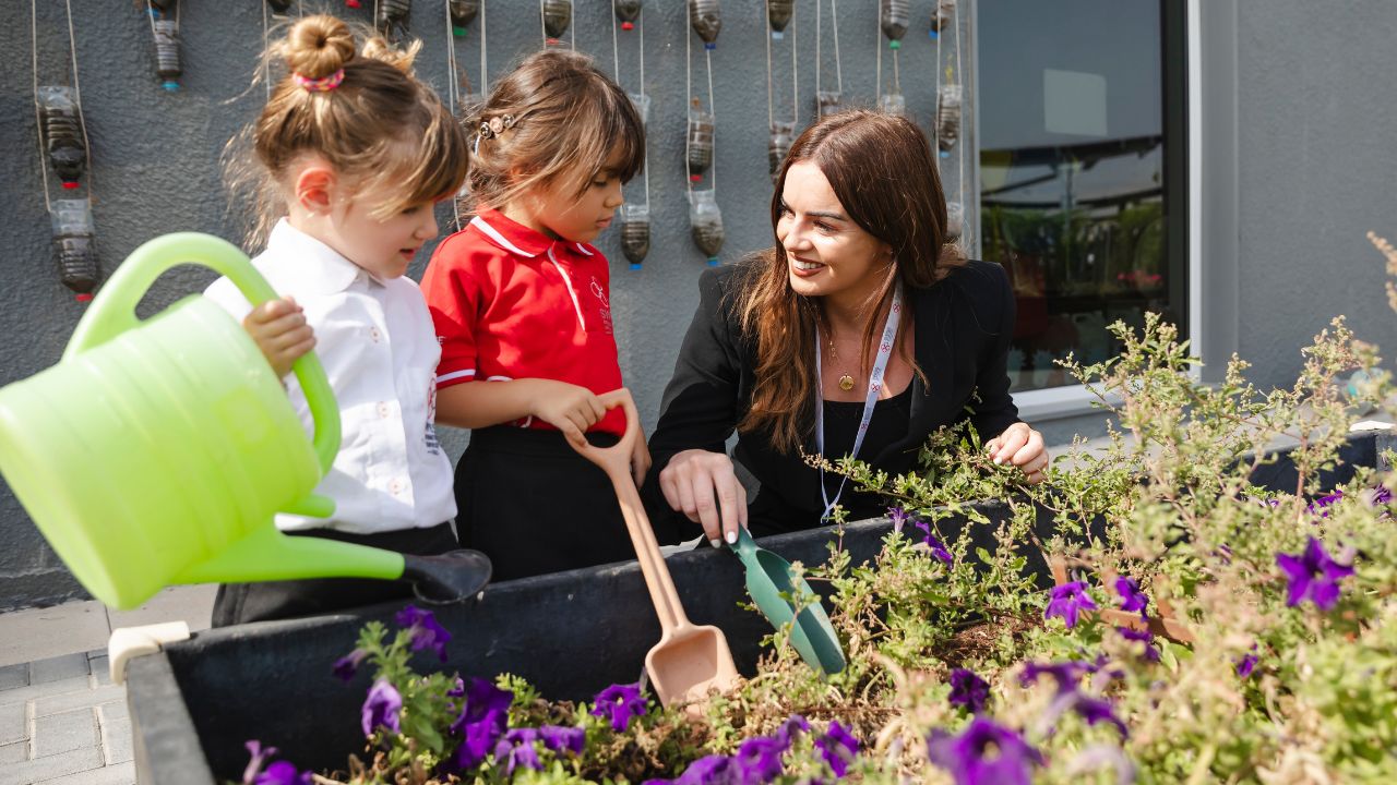 teacher with her young students watering the garden