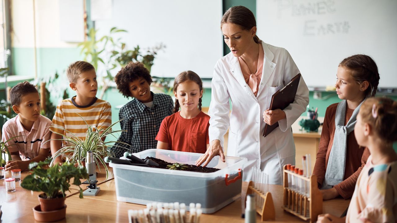School teacher explaining science project to children in classroom.