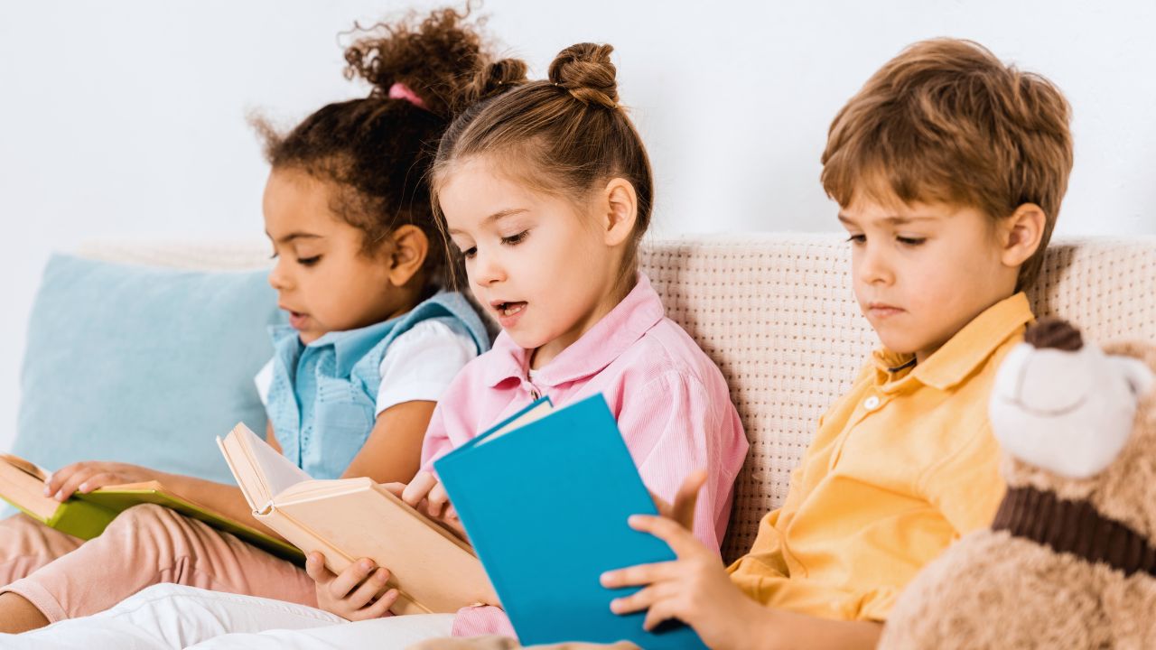Yalla Dubai Life Three children reading books together on a sofa for World Read Aloud Day.