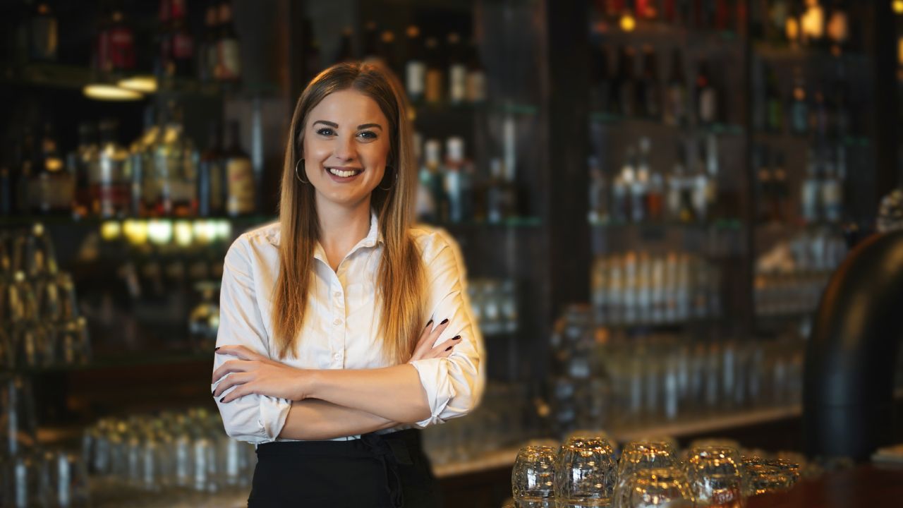 Smiling female bartender at The Gulf Bar Show in Dubai, showcasing vibrant nightlife and hospitality.