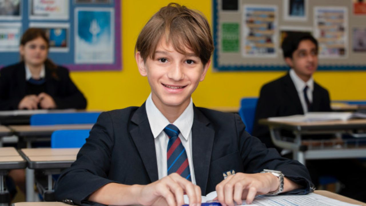Young student smiling in classroom during exam season.