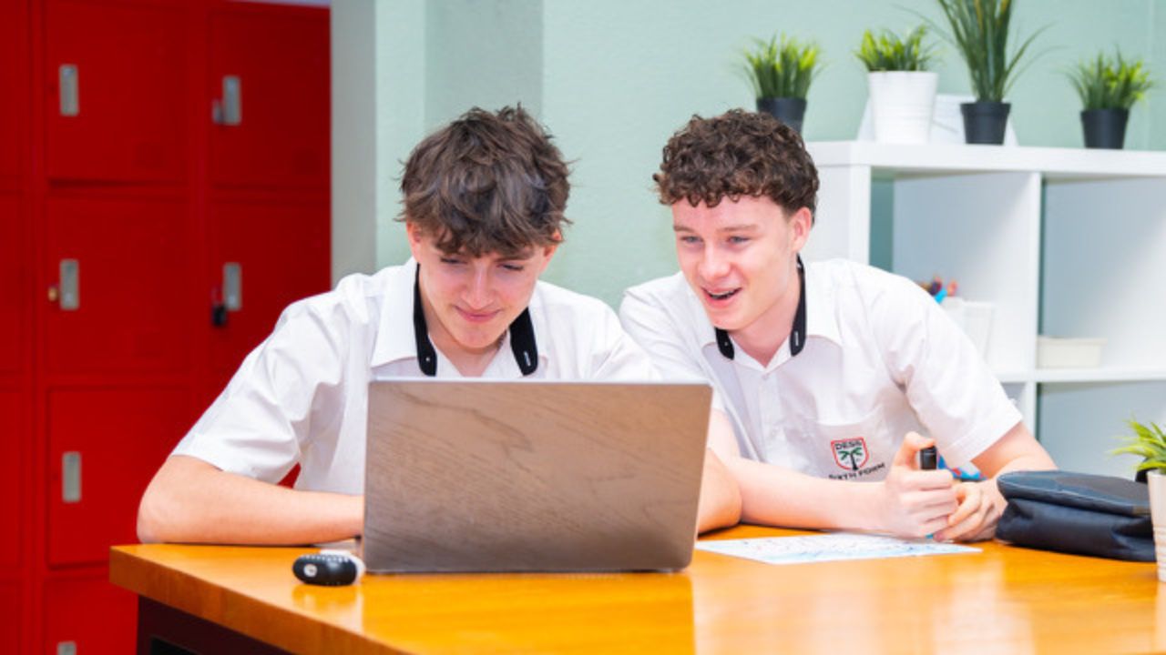 two male students looking at a laptop 