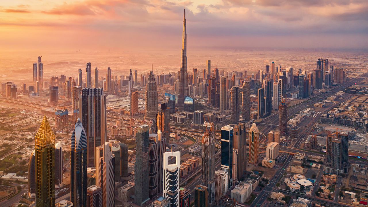Dubai skyline at sunset with iconic skyscrapers. Aerial view of Dubai's cityscape featuring tall buildings and the Burj Khalifa at sunset.