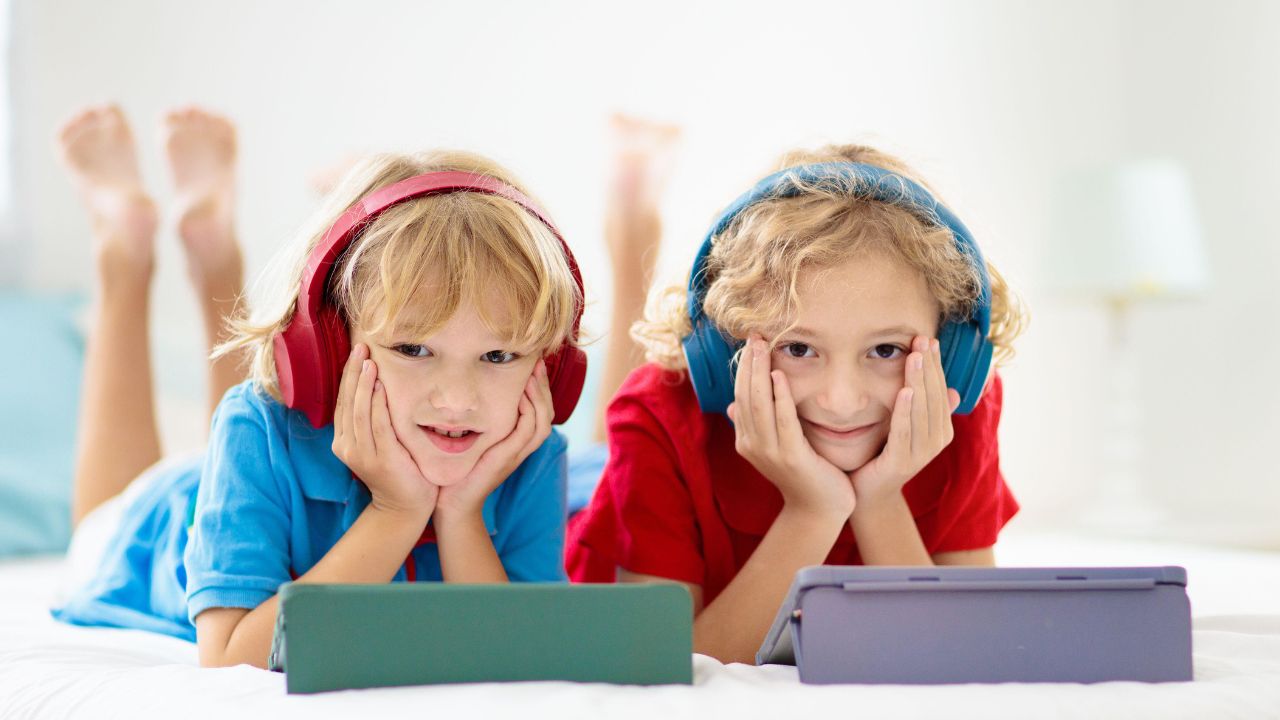Kids enjoying online learning with headphones and tablets in a bright room. Children using tablets for online education, engaging in digital learning activities at home.