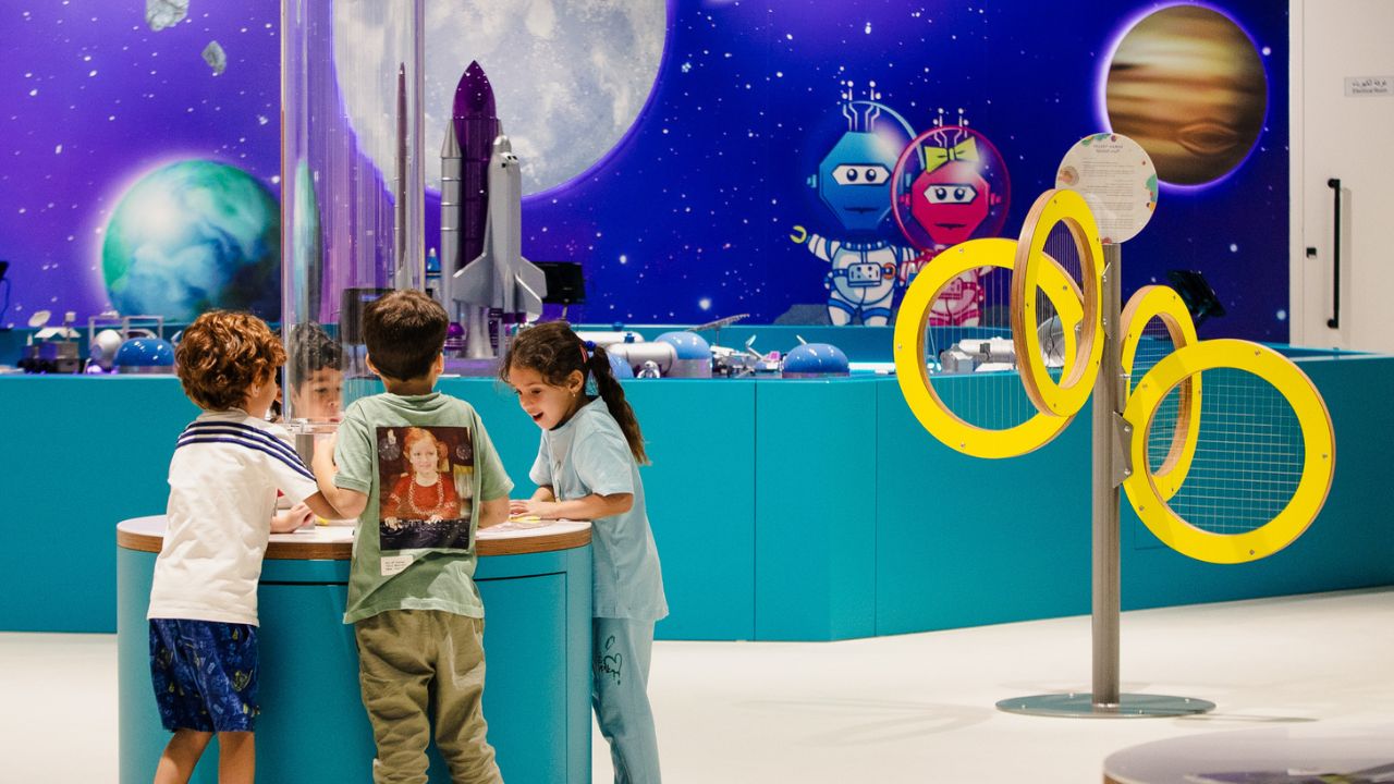 Space-themed children’s play area with kids engaging in activities, planets, and rockets in the background. Kids exploring space activities in a colourful, educational play zone.