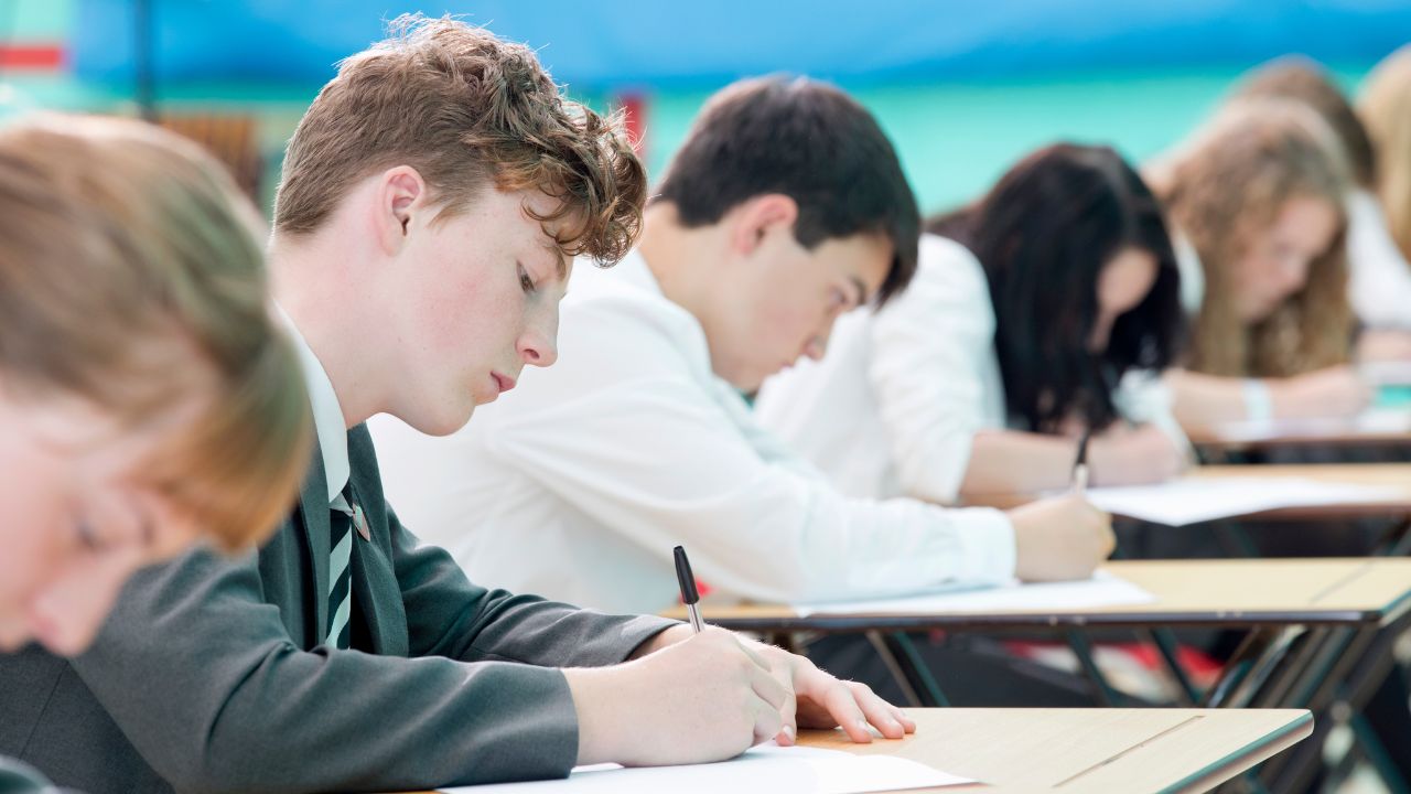 Students sitting at desks outdoors during exams.
