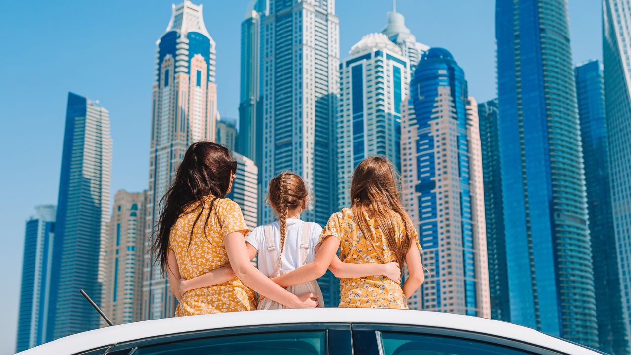 family sitting on top on their car looking at dubai