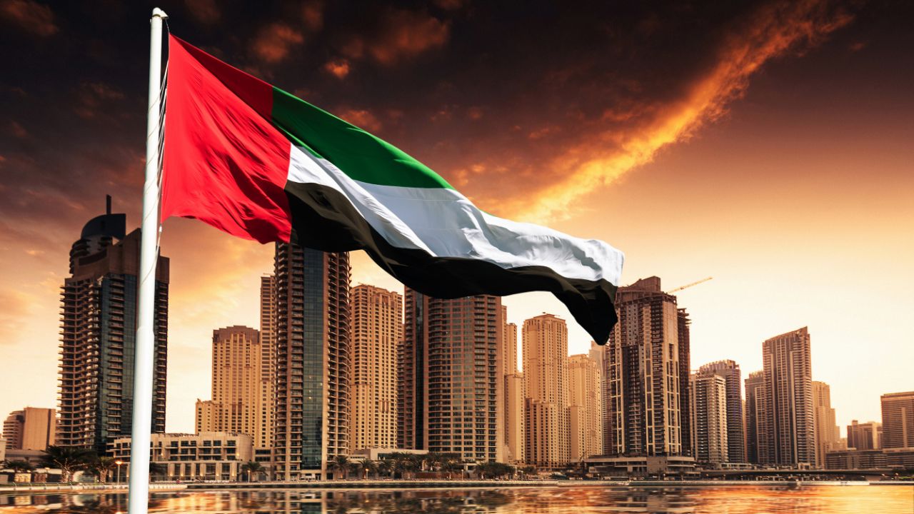 Dubai flag flying over city skyline at sunset. Flag of Dubai waving with cityscape background during sunset.