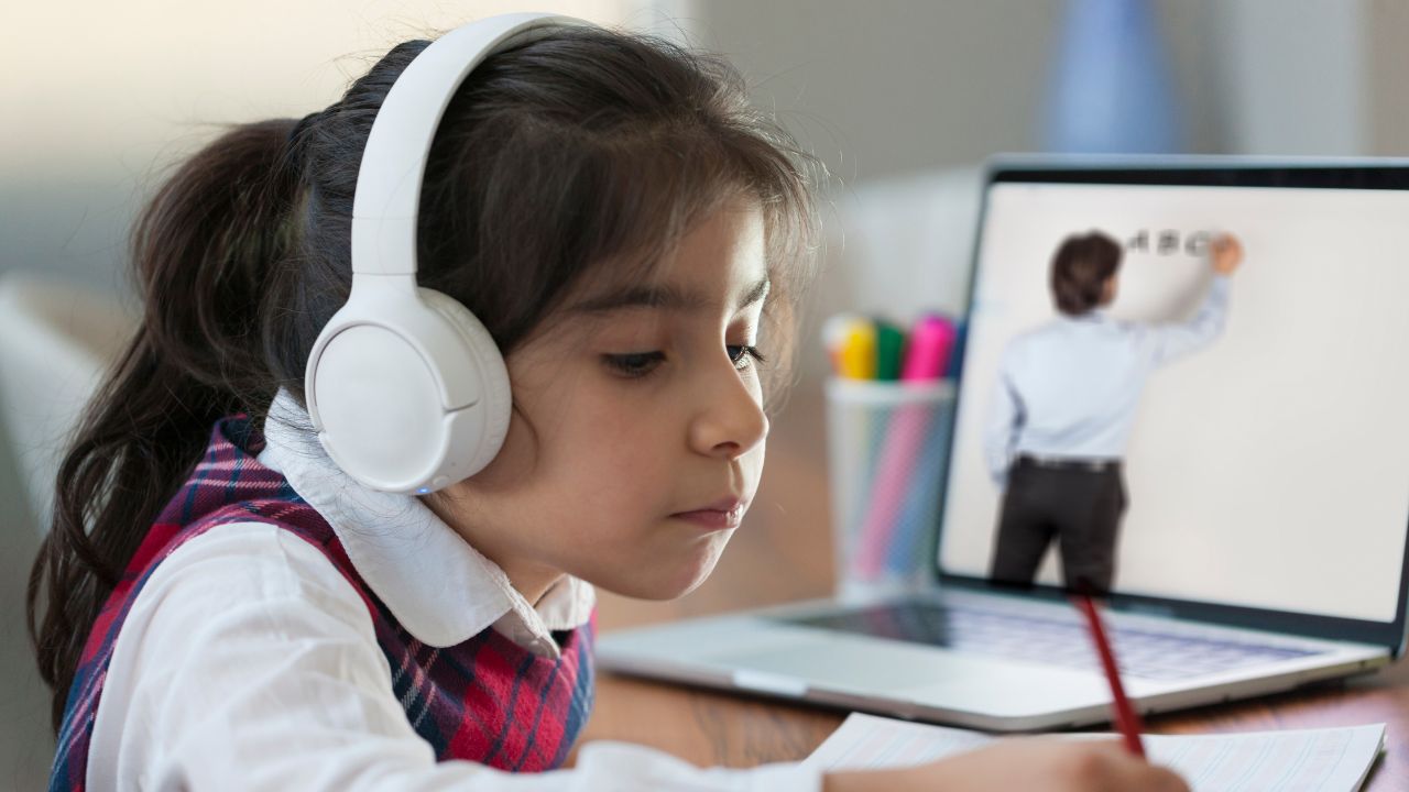 Young girl with headphones studying online at home.