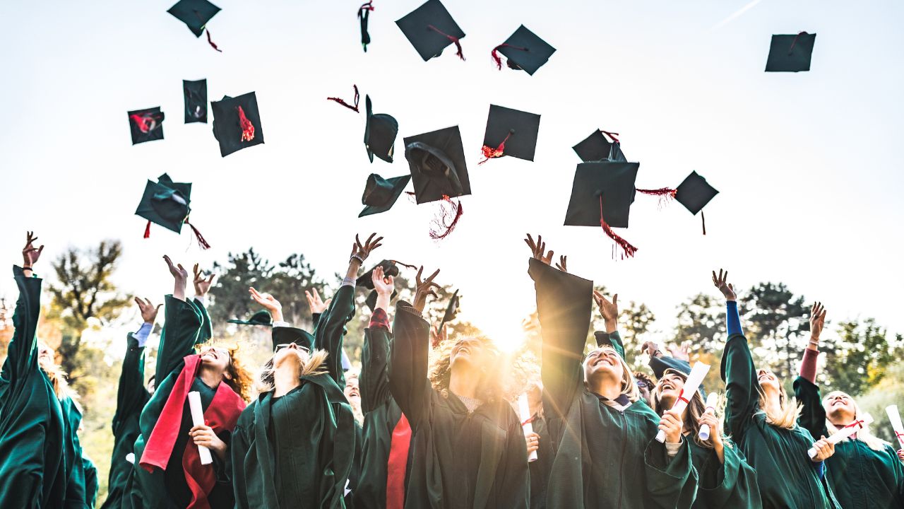 Graduates in caps and gowns celebrating their achievements outdoors, symbolising hope and future opp.