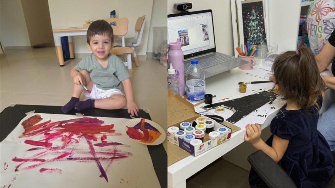 Young girl painting on large paper with colourful paints and brushes.