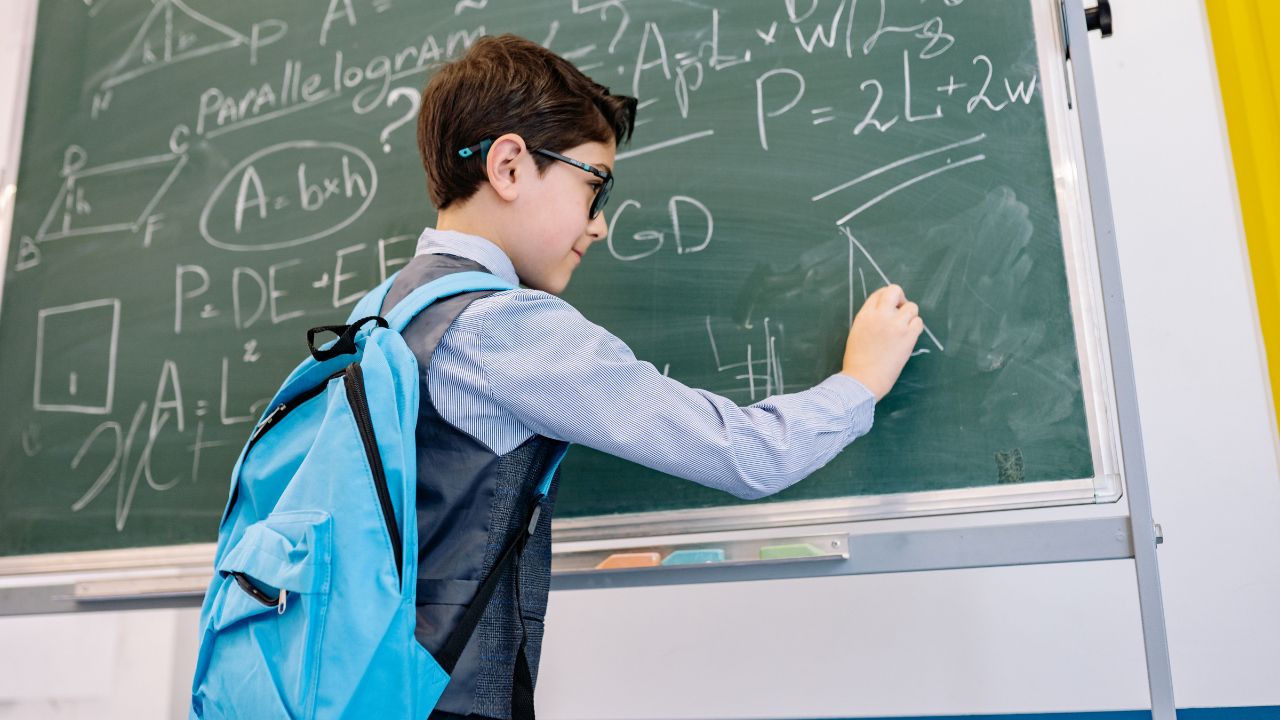 kid answering math on the black board
