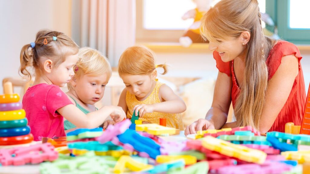 Happy teacher with children engaging in educational play in a bright classroom.
