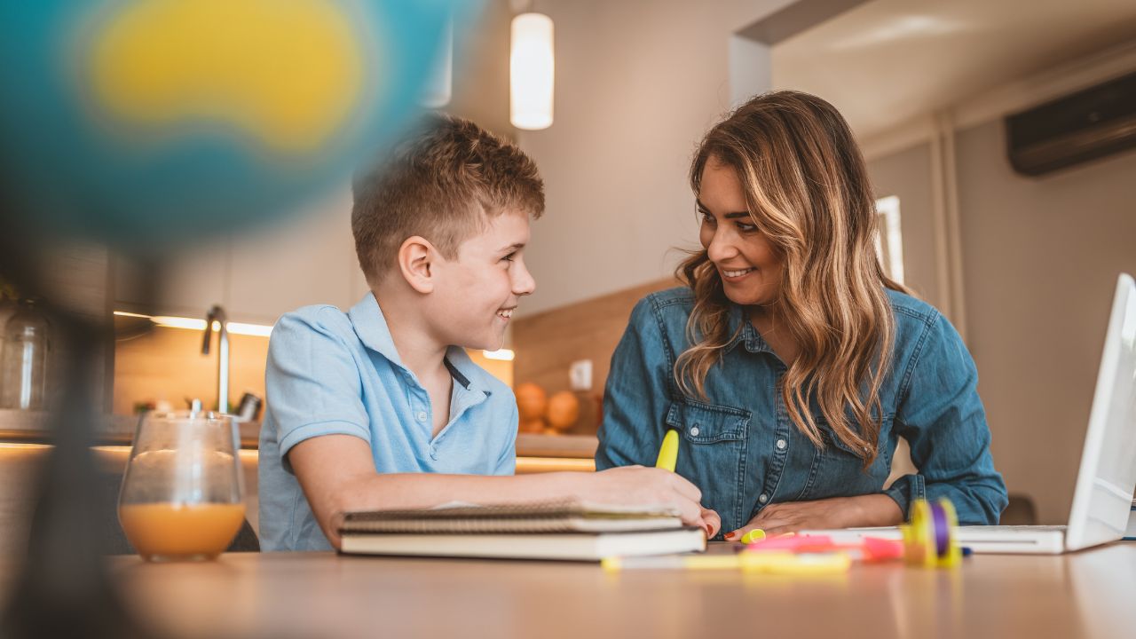 Happy mother and son studying online at home.