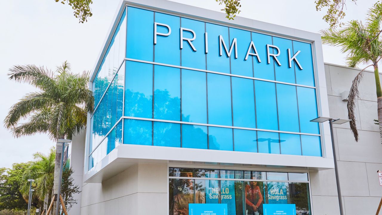 Primark Dubai Store Opening Modern Primark store in Dubai with glass facade and palm trees.