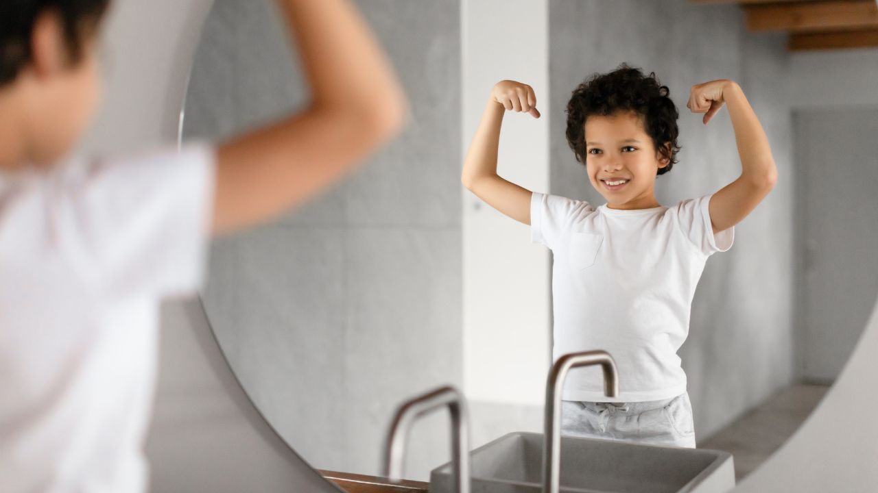 Healthy childhood confidence in Dubai. child looking in the mirror flexing