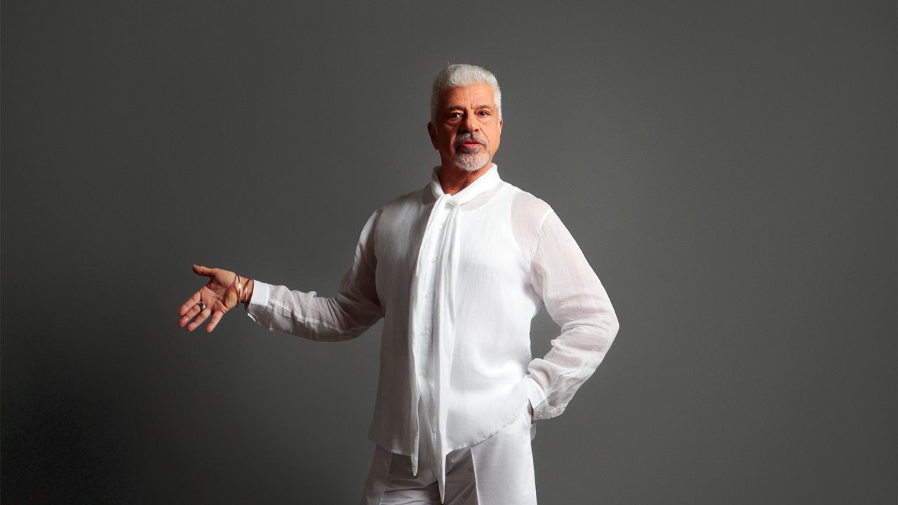 Elegant man in white traditional attire posing confidently.