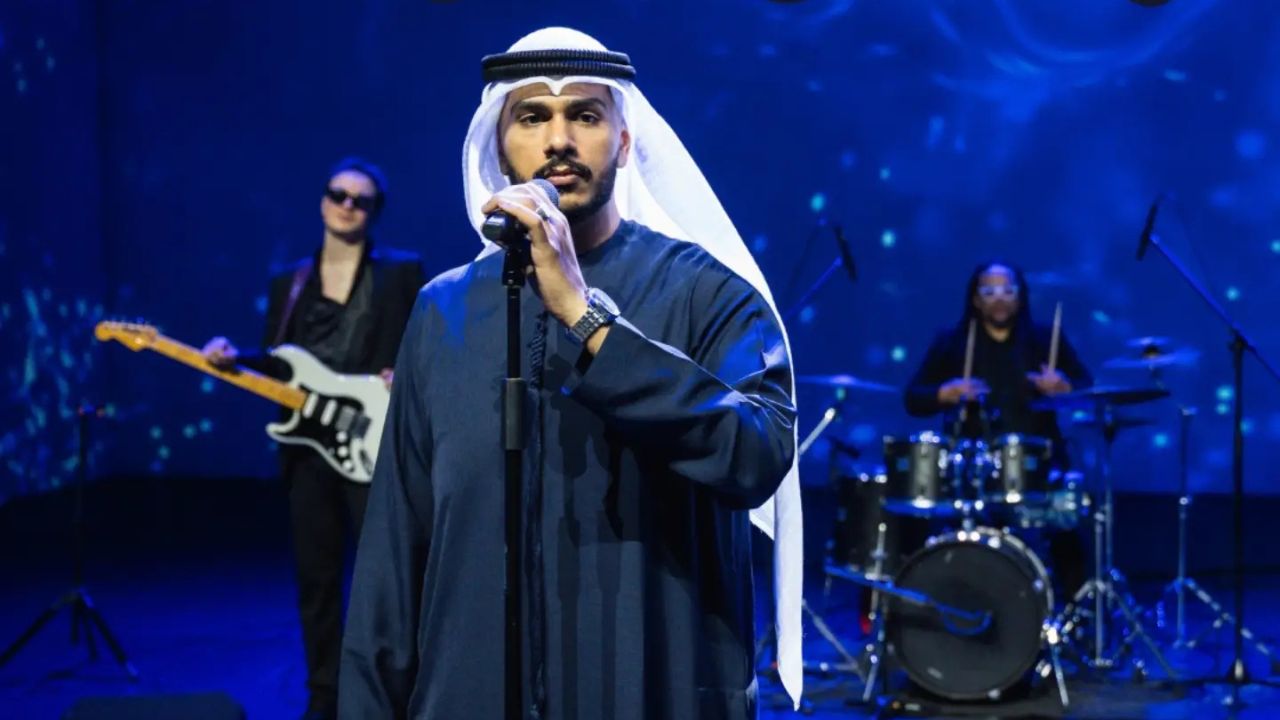 Almaydee on the microphone with band on the background