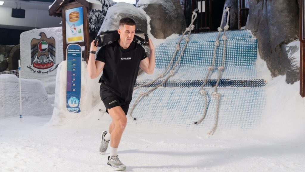 Young man carrying backpack at snow park, Dubai, enjoying winter activities.