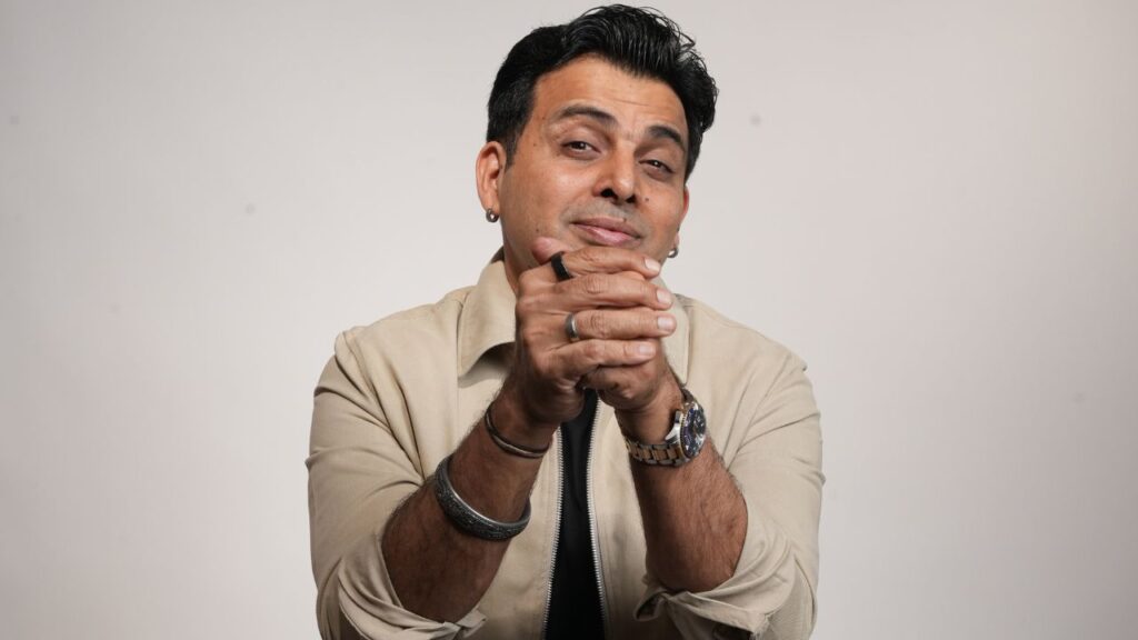 Male comedian with confident expression and hand gesture.