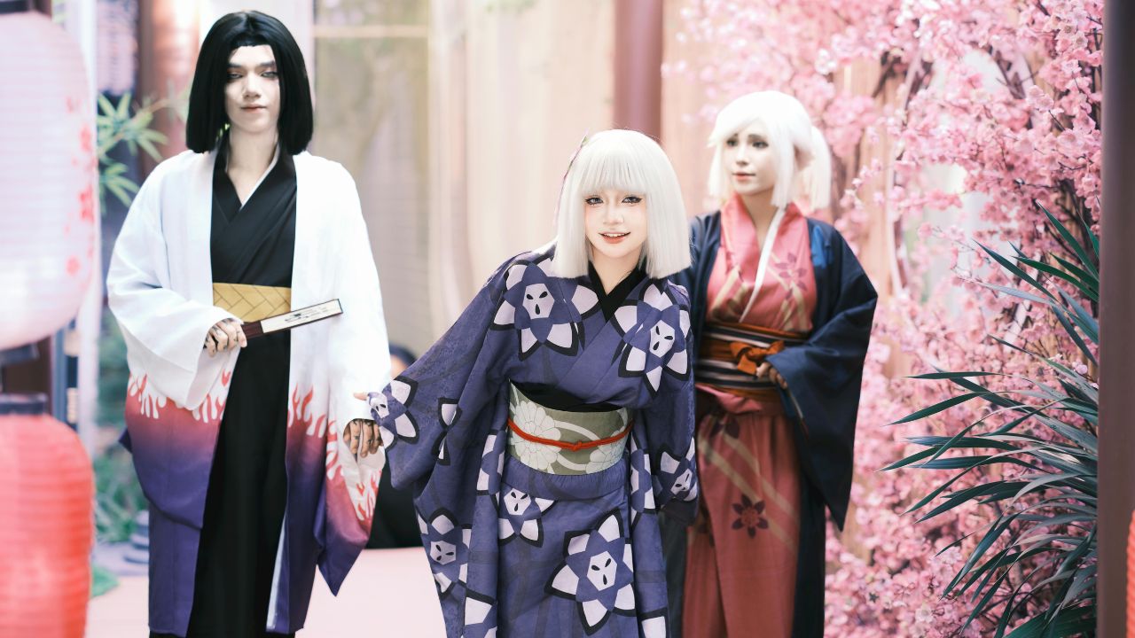 three individuals wearing kimono costume with cherry blossoms as there background