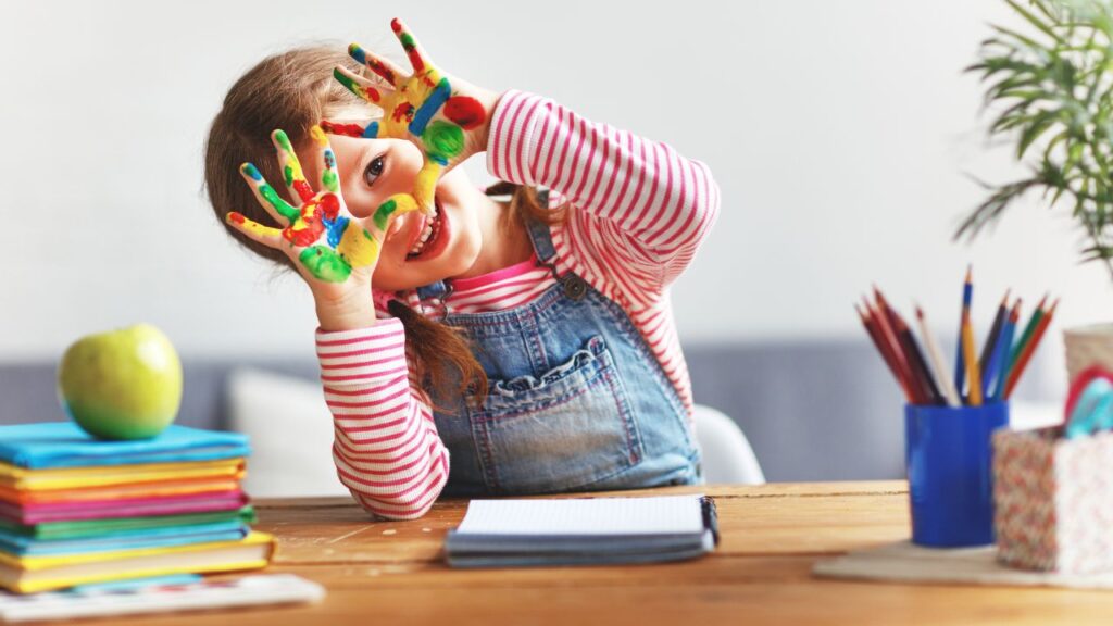 child smiling with painted hands