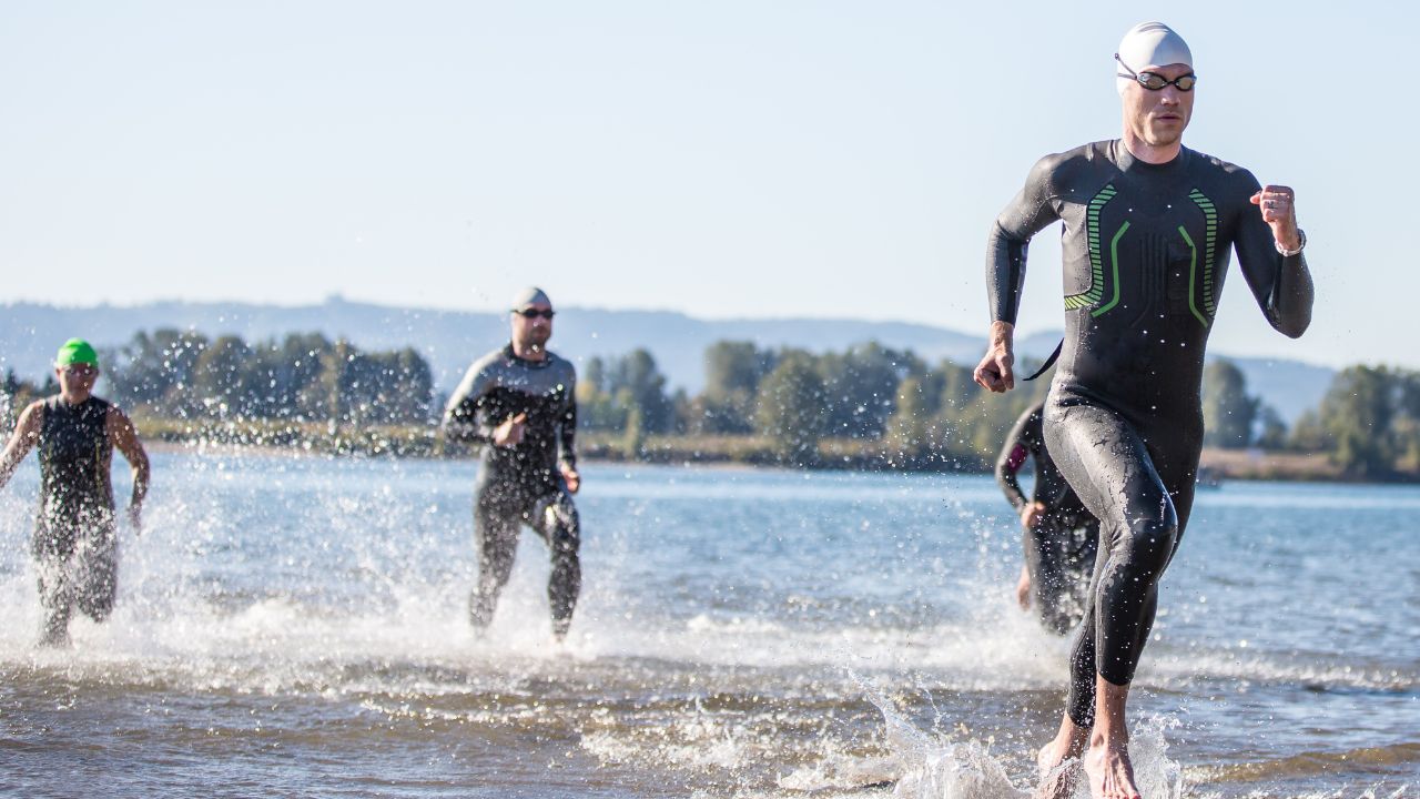 men during triathlon race getting out of the sea after swimming