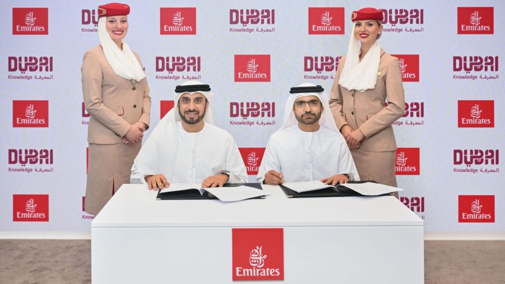 emirates khda signing, two men wearing kandura signing and two flight attendants on the back