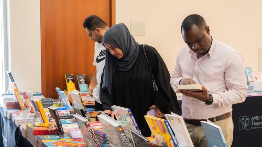Emirati woman, 2 men browsing through books