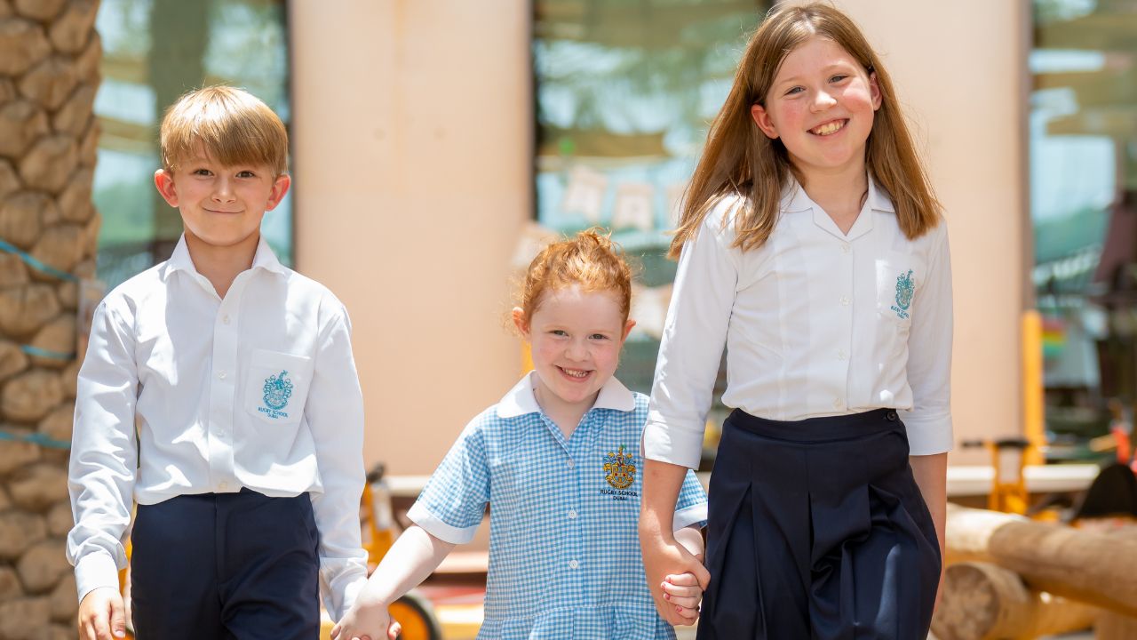 three students holding hands smiling
