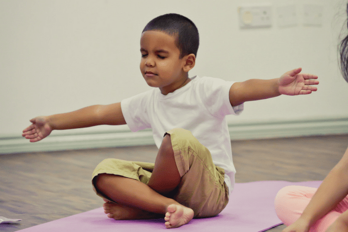 a kid is doing yoga at yoga mat in his house