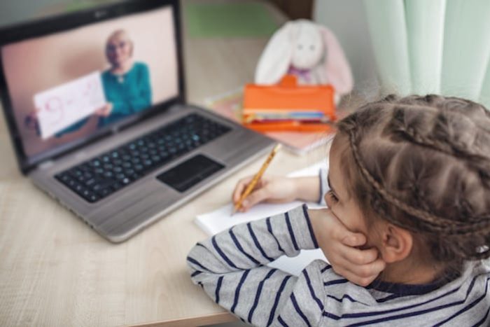 Pretty stylish schoolgirl studying homework math during her online lesson at home, social distance during quarantine, self-isolation, online education concept, home schooler