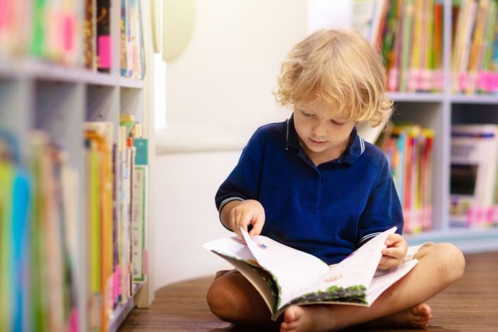 child reading a book in school library